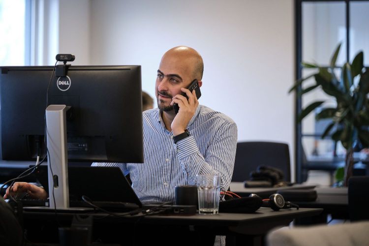 Mand taler i telefon foran sin computer som et optimeret mod collaboration og AI løsnigner
