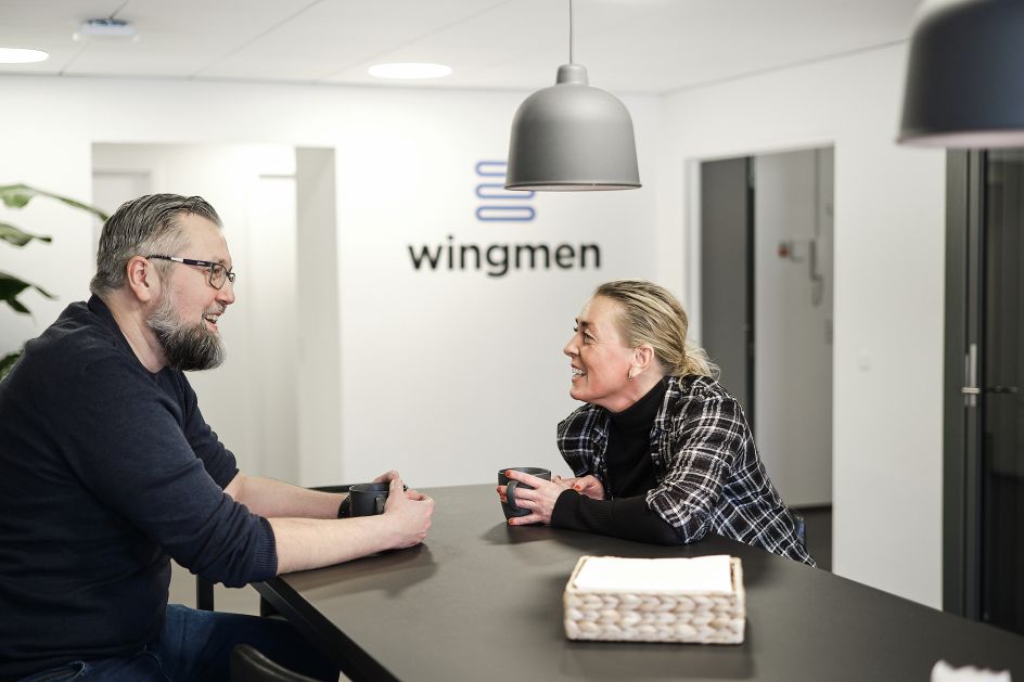 to wingmen sidder med en kop kaffe og taler med hinanden